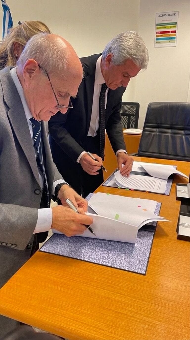 Two clients signing AXIOM BANK account documents with an adviser beside them